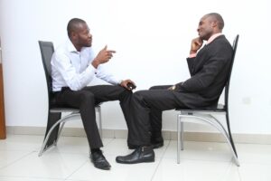 A self-improvement life coach works with a client on setting personal goals in a bright office